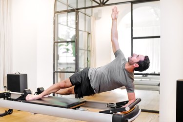 Fit man doing pilates side elbow plank exercises