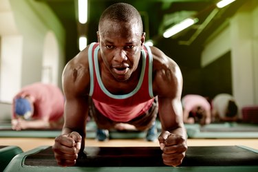 Front view of a sweaty man holding a plank position in a workout class