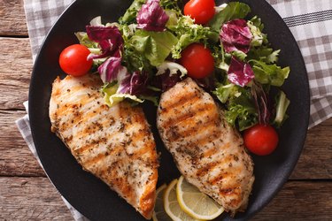 Close-up view of grilled chicken breast with mixed salad and tomatoes to avoid upset stomach