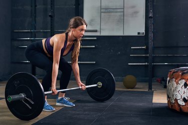 Woman Lifting Heavy Barbell in CrossFit Gym