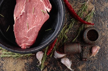 Raw beef steak with spices and herbs.