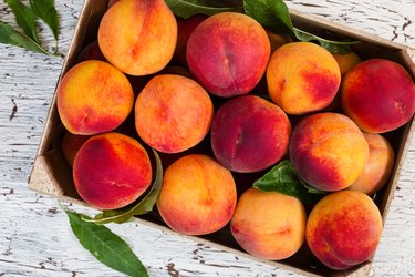 Fresh organic peaches in wooden crate viewed from above
