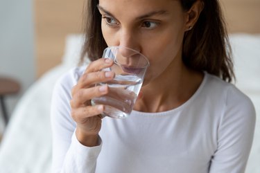 特写镜头女子拿着玻璃杯喝静水或矿泉水