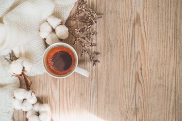 Background with warm sweaters and cup tea. Cozy still life in warm shades, space for text, Autumn winter concept. Copy Space.