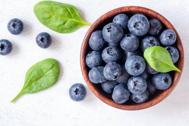 Fresh blueberries in bowl on white background, top view