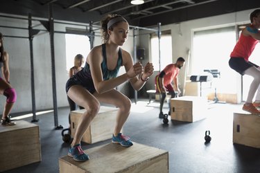 Focused woman jump squats in gym exercise class