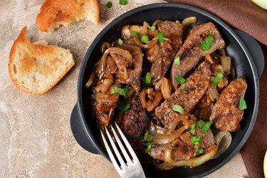 Fried iodine-rich beef liver with onions and apples on a concrete background