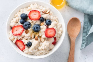 Oatmeal porridge with berries and almonds in bowl, top view