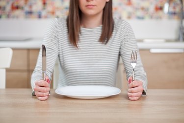 Diet concept of a hungry woman with an empty plate