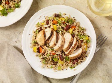 overhead photo of white bowl of grilled chicken with quinoa and brown rice
