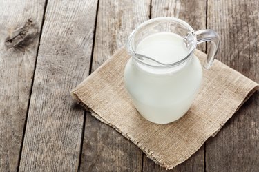 glass jug with milk on wooden background