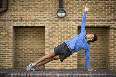 Man stretching in front of brick wall, Wapping, London, UK