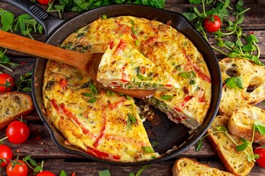 Frittata made of eggs, potato, bacon, paprika, parsley, green peas