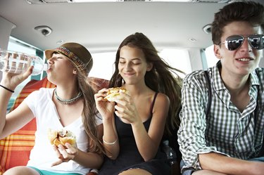 Three teenage friends having a snack in car