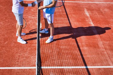 Men greeting while standing on tennis court during summer match