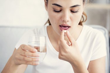 woman taking a vitamin with a glass of water