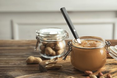 Glass jar with peanut butter on kitchen table