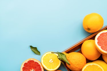 Various citrus fruit on blue background top view with copy space