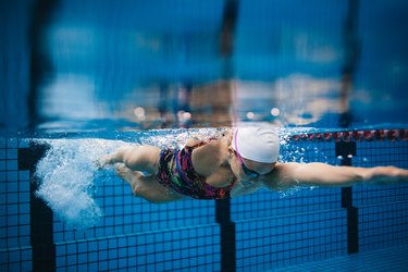Female swimmer in action inside swimming pool.