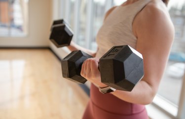 Low Section Of Woman Exercising With Dumbbells At Home