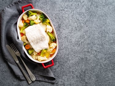 Fish cod baked in the oven with vegetables - healthy diet healthy food. Gray stone background, copy space, top view.