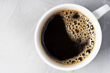 Close-up of a mug of black coffee on white table