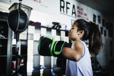 Young female boxer working on double ended bag in boxing gym after coughing up jelly balls and salty mucus