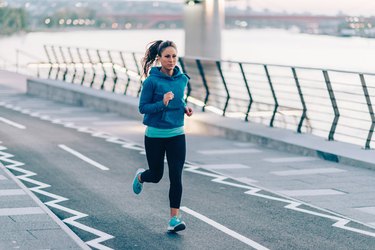 Urban fitness. Woman running by the river