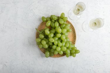 Bunch of ripe green grapes and  two glasses of white wine