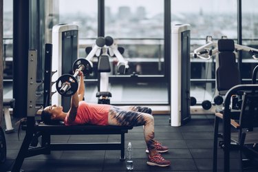 Young determined sportswoman exercising bench press in a gym.