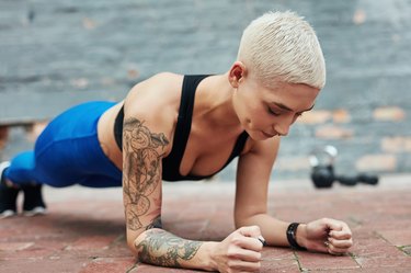 Women doing a plank variation with kettlebells in the background