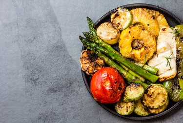 Grilled vegetables, pineapple slices and fresh cheese on iron plate