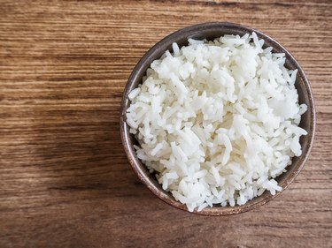 Cooked jasmine rice in a bowl on wooden table