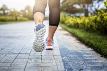 View of a woman's feet as she runs in the park, trying to lower her blood pressure to an ideal blood pressure reading for a woman