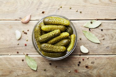 Pickled gherkins or cucumbers on wooden rustic table. Flat lay.