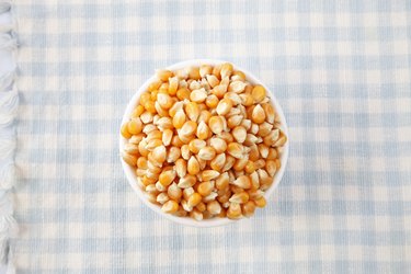 Close-Up Of Unpopped Popcorn Kernels In Bowl On Tablecloth