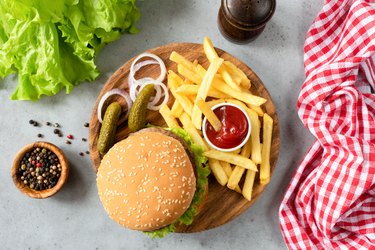 Burger with sesame, fries, pickles and lettuce salad