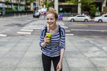 Young woman drinking green juice, a healthy alternative to energy drinks
