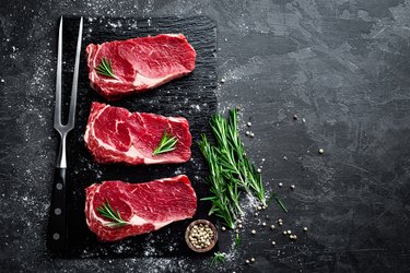 Raw meat, beef steak on black background, top view