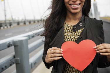 A smiling African-American woman holding a red paper heart