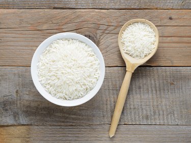 Jasmine rice in bowl and spoon on wooden table