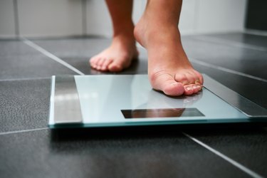 a person's foot stepping onto a glass bathroom scale