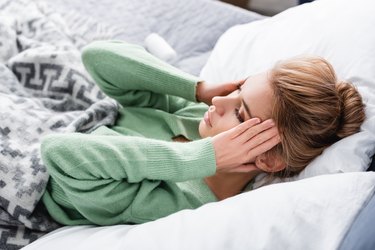 tired woman having headache and lying in bed in the morning