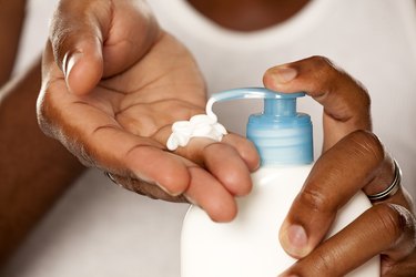 close up on hands of young Black man squeezing a body cream from a pump