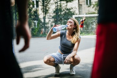 Young Woman Taking Break From Basketball Game To Drink Water