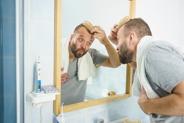 Man using comb in bathroom