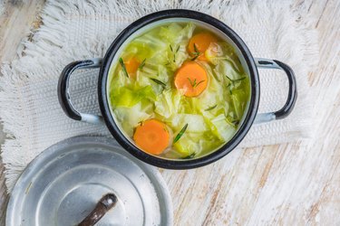 Top view of cabbage soup in a pot on a wooden table