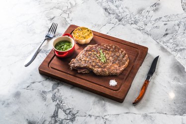 Rib Eye steak on wooden cutting board with small side dishes
