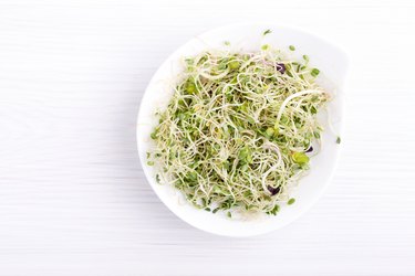 Mix of food bean sprouts - alfalfa, radish, clover in a bowl. Micro greens on white. Healthy eating. Top view.