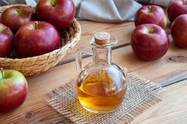 A bottle of apple cider vinegar with apples